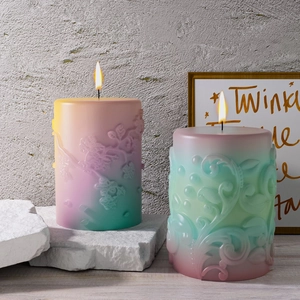 Lighted gradient pillar candles with floral relief on textured stone surface
