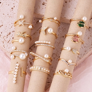 Detail of gold fashion rings set featuring pearls, zircon and colorful enamel floral charms