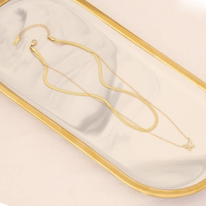 Double-layered gold stainless steel necklace with butterfly pendant on marble tray