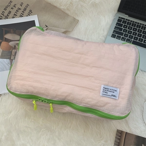 Close-up of pink grid travel organizer bag with contrasting green zipper and woven label