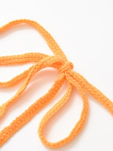 Detailed macro view of orange handmade knitted fabric with drawstring texture