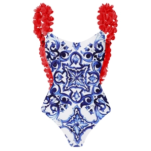 Detail of red 3D floral accents and blue majolica tile print on a one-piece swimsuit