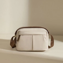 Detail of beige and brown contrast strap and secure zipper on women's soft leather bag