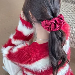 Close-up of wine red satin scrunchie showing glossy pleated silk texture in hair