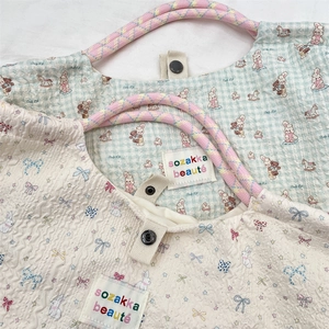 Detail of quilted canvas tote with cute cartoon patterns and colorful woven handles