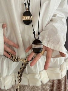 Detail of two oval wooden pendants with intricate gold and silver metal inlay craftsmanship