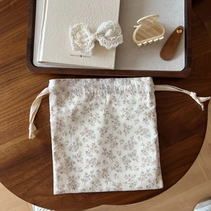 Close-up of vintage floral drawstring bag with lace hair clips on a rustic wooden tray