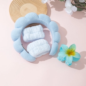 Detail view of light blue puffy spa headband set with wristbands and flower hair claw clip
