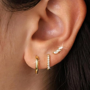 Detailed view of three-piece gold earring set with zircon accents on ear model