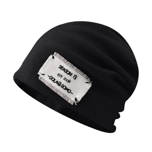 Black knit beanie with vintage alphabet patch and vertical ribbed texture on white background