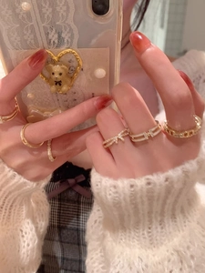Close-up of golden bow-knot pearl rings with sparkling gemstones on a model hand