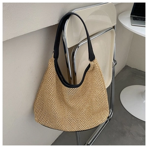 Detail of woven straw shoulder bag with black leather trim hanging on a metal chair