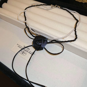 Detail of double-layer necklace with black fabric rose, white pearls, and satin ribbons
