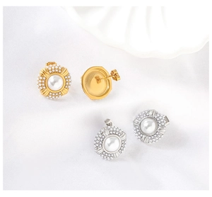 Detail of vintage round pearl stud earrings in gold and silver finish on white fabric