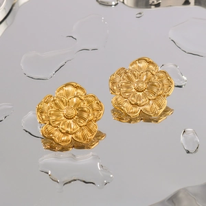 Minimalist gold flower petal earrings with detailed texture reflected on water droplets