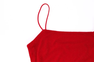 Dettaglio delle spalline sottili e del tessuto rosso lucido di un abito attillato sexy
