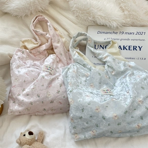 Detail of bear and floral print on satin tote bags in pink and light blue colors