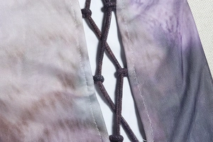 Macro view of purple gradient mesh fabric with criss-cross tie-up details on long sleeve suit