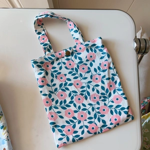 Detailed close-up of floral cotton handbag with gold snap button and pink flower prints