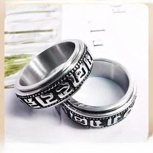 Macro view of rotating stainless steel band featuring engraved Om Mani Padme Hum mantras