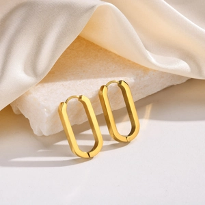 Detail of gold oval hoop earrings resting on marble with beige satin fabric