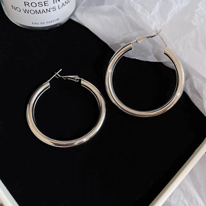 Macro shot of large silver hoop earrings with polished finish on black velvet display
