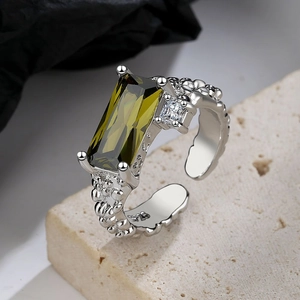 Macro shot of 925 silver ring featuring a green emerald-cut stone and adjustable band