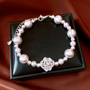 Detail of pearl bracelet with zircon flower pendant on black leather jewelry box