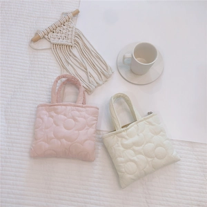 Dettaglio di mini borse trapuntate in rosa e bianco con ricamo floreale soffice