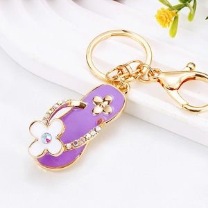 Close-up of purple flip-flop keychain with rhinestones, enamel flower, and gold lobster clasp
