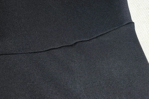 Gros plan du tissu en maille noire extensible avec coutures renforcées sur la robe
