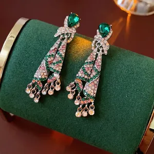 Vintage teardrop emerald earrings with crystal tassels on a green velvet background