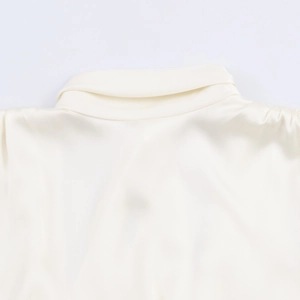 Close-up of the champagne satin blouse back featuring a delicate bow and glossy fabric texture