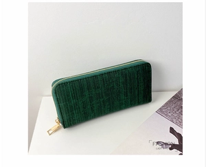 Close-up of deep green striped long wallet with elegant golden zipper hardware