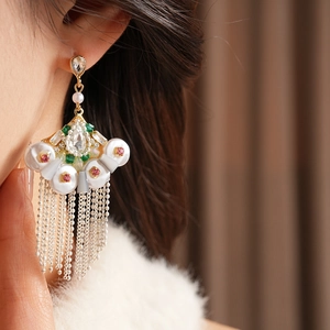 Close-up of vintage fan-shaped earrings with pearls and green rhinestones on a model