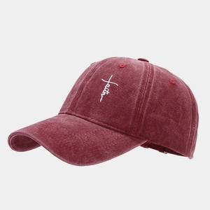 Detailed close-up of white faith cross embroidery on a burgundy washed cotton baseball cap