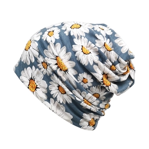 Detail of grey-blue slouchy beanie with large white daisy floral print and soft knit texture
