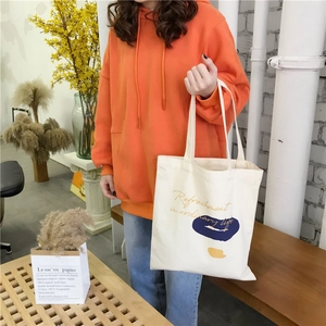 Detail of canvas tote bag with abstract color blocks paired with an orange hoodie