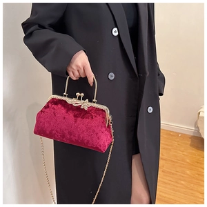 Detail of burgundy velvet shell bag with gold handle and sparkling rhinestone clasp