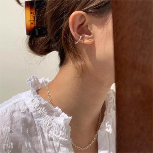 Close-up of elegant silver ear cuff and minimalist gold chain necklace on a model