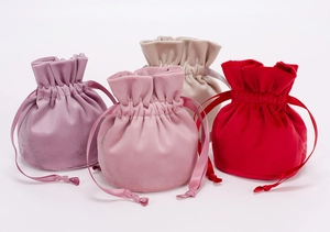 Detail view of colorful velvet drawstring pouches in lilac, light pink, beige, and red