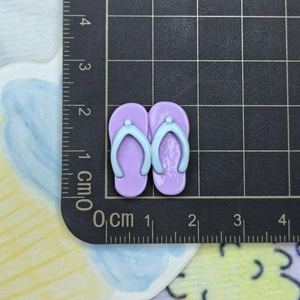 Detailed top view of 1.8cm purple resin flip-flop charms on a scaled measurement mat