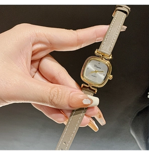 Close-up of elegant gold square case women watch with beige leather strap and white dial