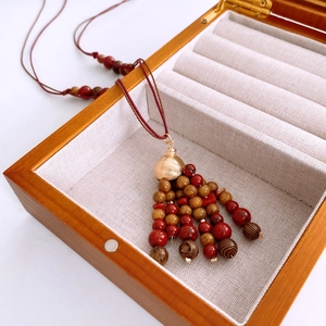 Macro detail of red and brown wooden beads with a tassel on a gray velvet tray