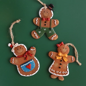 Three resin gingerbread man Christmas tree ornaments with burlap strings on green background