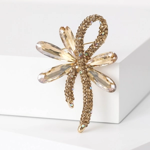 Elegant gold bow brooch with champagne crystals and brown rhinestones on white display