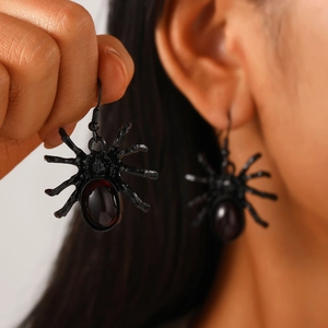 Close-up of black spider earrings with dark red gemstone for Gothic Halloween look