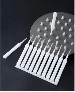 Close-up of 12 white shower head nozzle cleaning brushes on a black background