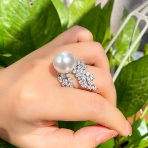 Detailed view of luxury white pearl ring with pavé diamond setting on hand