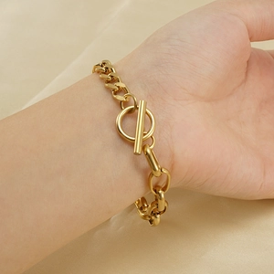 Bracelet chaîne en acier inoxydable doré avec fermoir OT porté sur satin soyeux